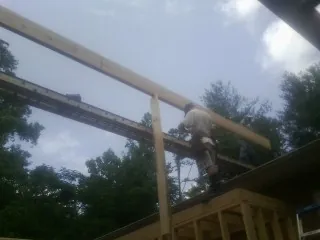 Carpenter setting a ridge beam over a new addition frame — Ice Dam Removal by Roofing Brothers in Bells