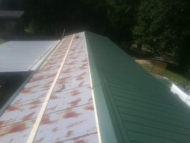 Old rusted panels beside newly installed green metal roofing — Wind Damage Roof Repair by Roofing Brothers in Bells