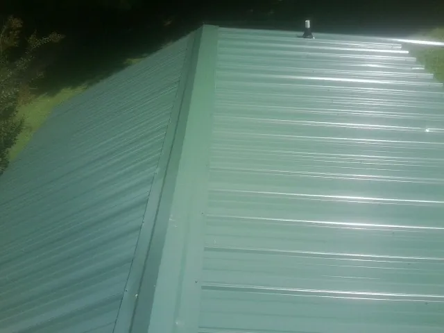 New green metal panels meeting at the ridge of a roof — Flat Roof Repair work by our crew in Bells