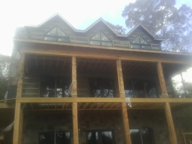 Dormers and porch framing on a large log home under construction — Roof Coating work by our crew in Bells