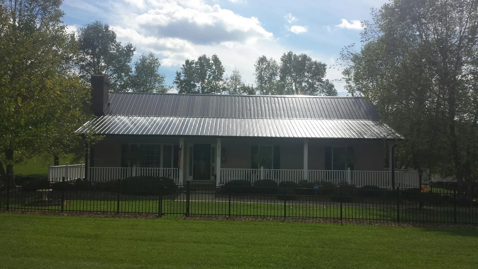 Gray metal roof on a brick ranch with a full width front porch — Gutter Guard Installation work by our crew in Bells
