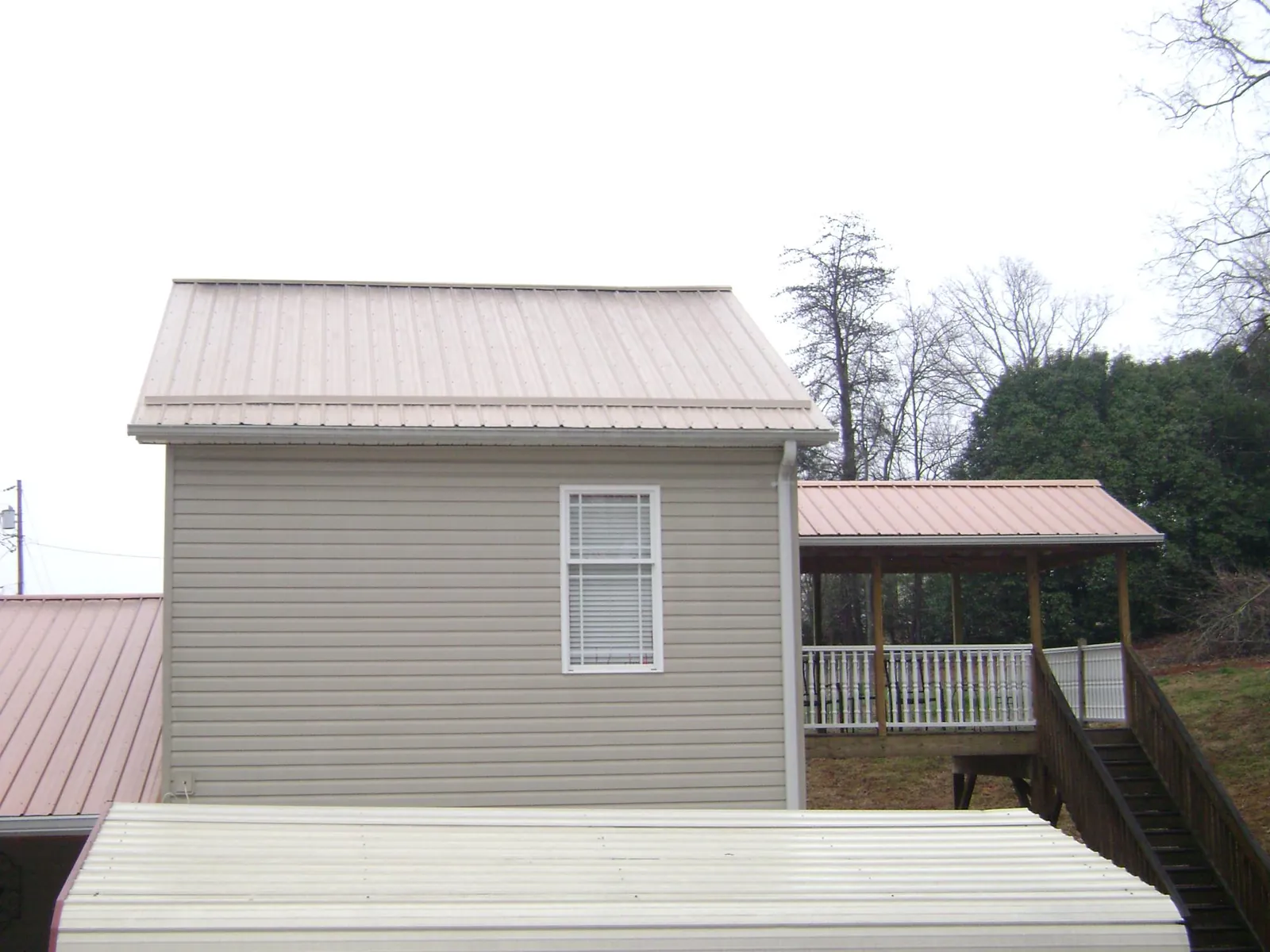 Tan metal roofs on a two story addition and attached porch, from a Roof Replacement job in Bells