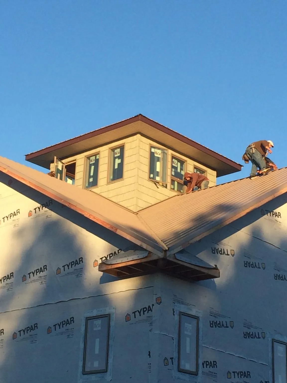 Roofers working around a rooftop cupola on a new metal roof at sunset — Roof Waterproofing in Bells by Roofing Brothers